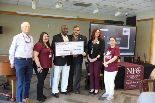 NFC Foundation Board Chairman Hal Thomas, NFC student worker Caroline Wynn, NFL Player Jessie Solomon, NFC President Jon Grosskopf, NFC Director of Resource Development Traci McClung and NFC Coordinator of Scholarship Brienna Valentine hold check